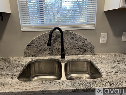 A kitchen sink with a black faucet and a granite countertop.