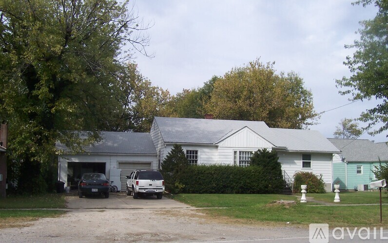 A white house with a garage and two cars parked in front.