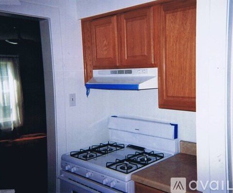 A white stove with blue trim is in a kitchen with wooden cabinets.