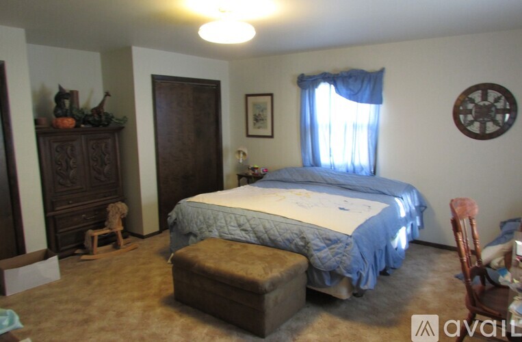 A bedroom with a bed, dresser, and window.
