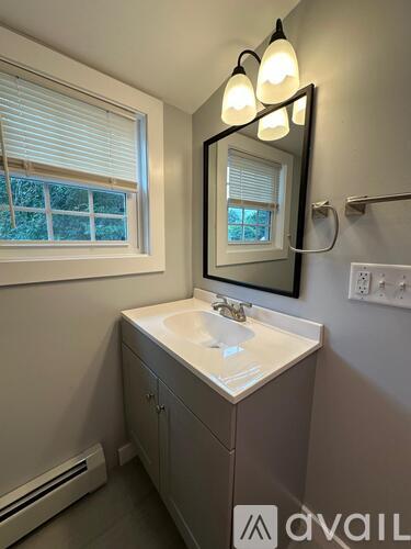 A bathroom with a sink, mirror, and window.