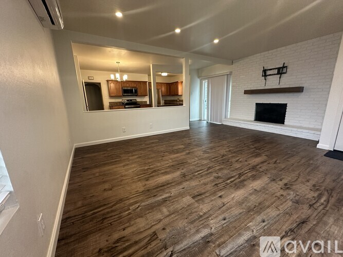 A spacious living room with wood flooring and a fireplace.