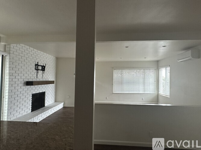 A room with a fireplace and a window with blinds.
