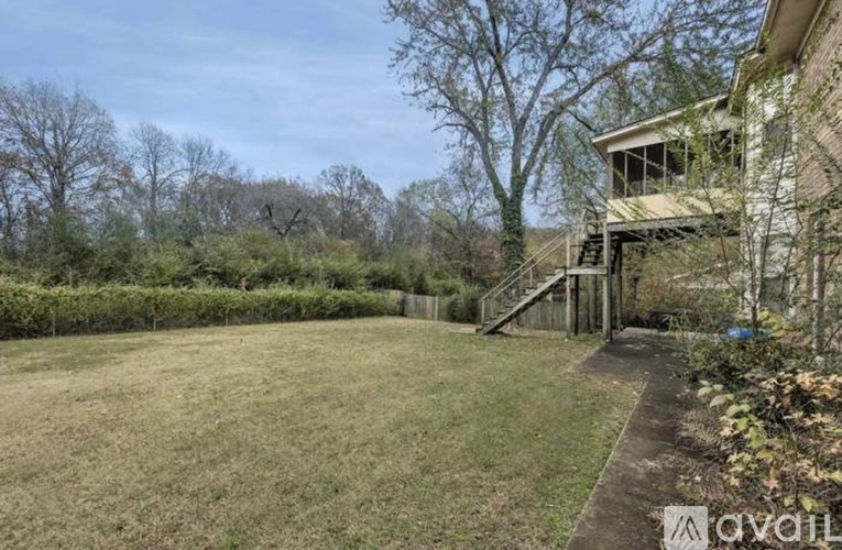 A backyard with a lawn, trees, and a house.
