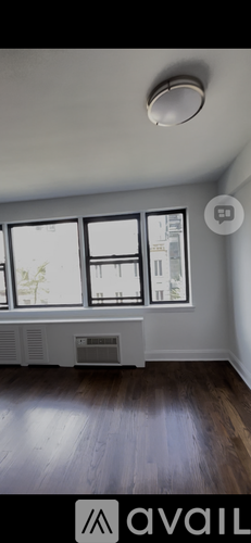 A room with wooden floors and a window with a view of a building outside.