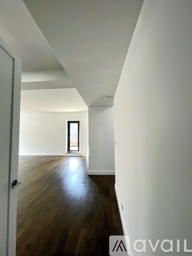 A hallway with wooden floors and white walls.