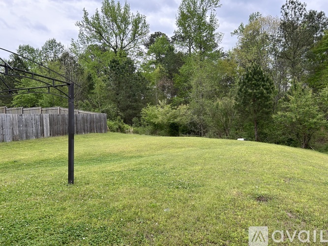 A grassy field with a wooden fence and trees in the background.