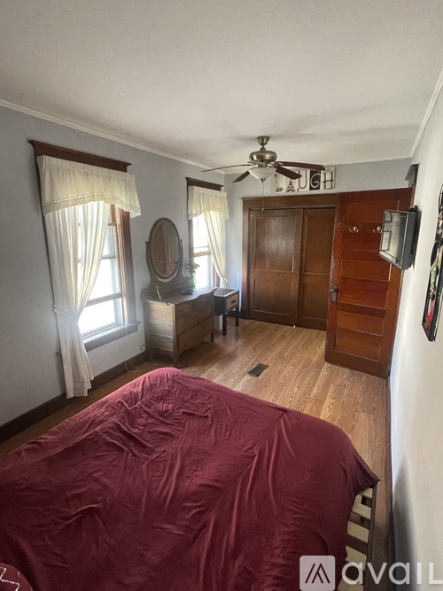 A bedroom with a bed covered in a red blanket.