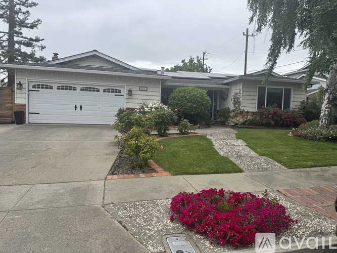 A house with a white garage door and a driveway with a flower bed.