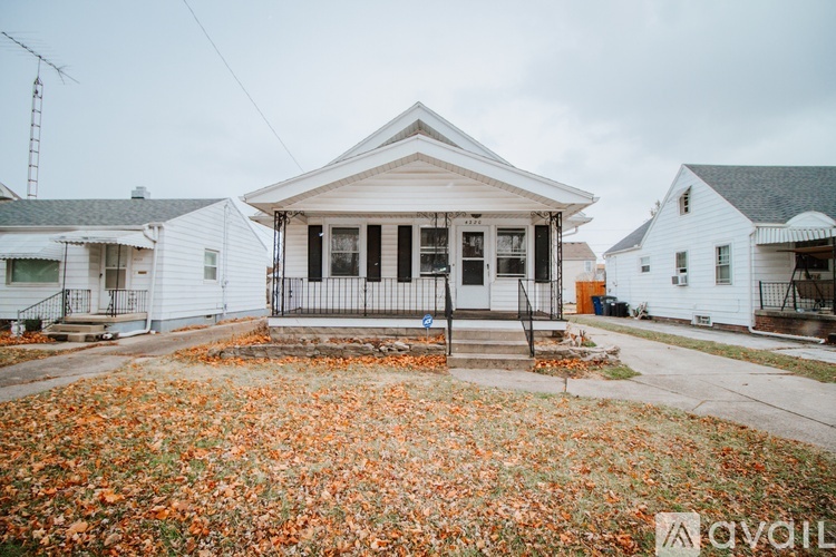 A house with a front yard covered in fallen leaves.
