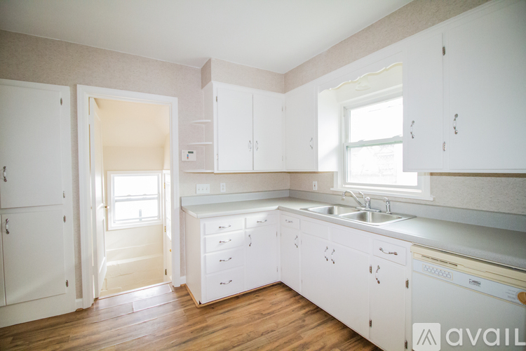 A kitchen with white cabinets and a wooden floor.