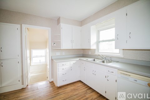 A kitchen with white cabinets and a wooden floor.