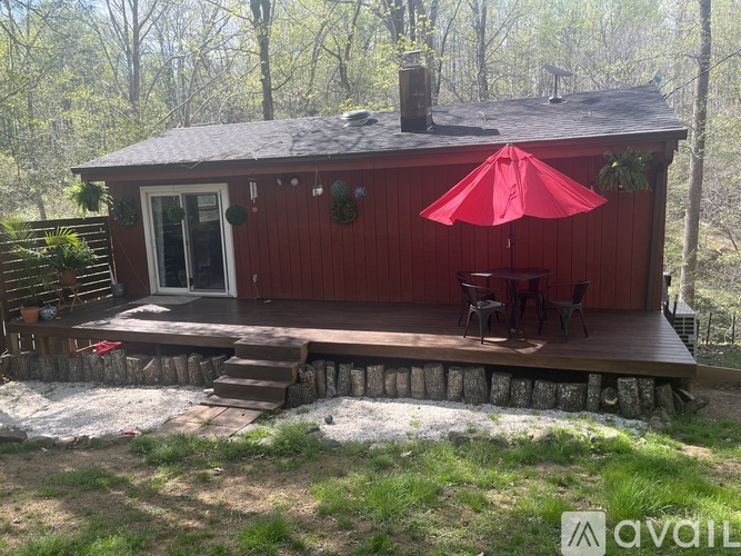A red house with a red umbrella on the porch.