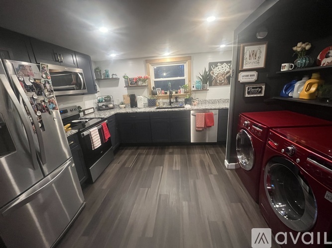A modern kitchen with dark wood floors and stainless steel appliances.