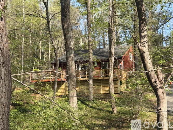 A wooden cabin is nestled in a forest of tall trees.