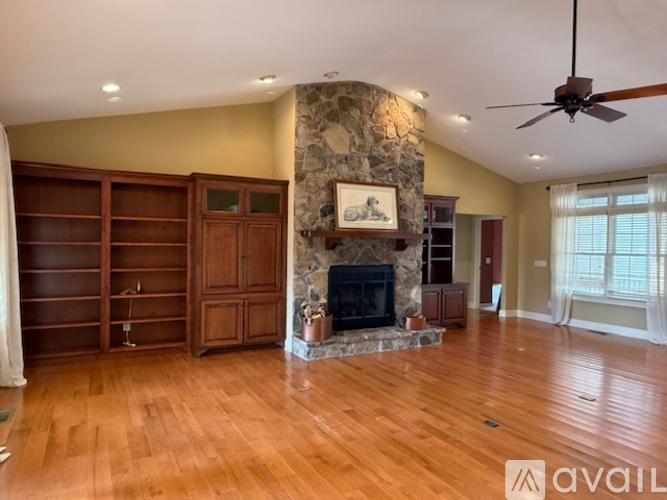 A living room with a stone fireplace and wooden floors.