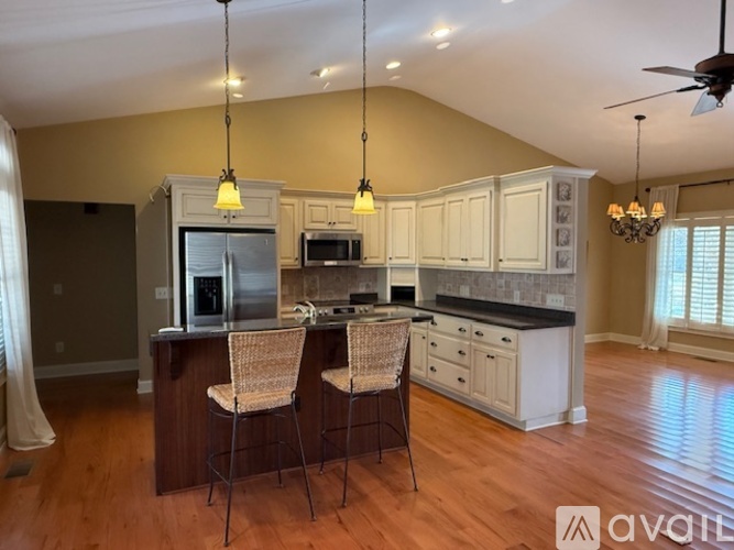 A kitchen with a refrigerator, microwave, and oven, with a bar area in front of it.