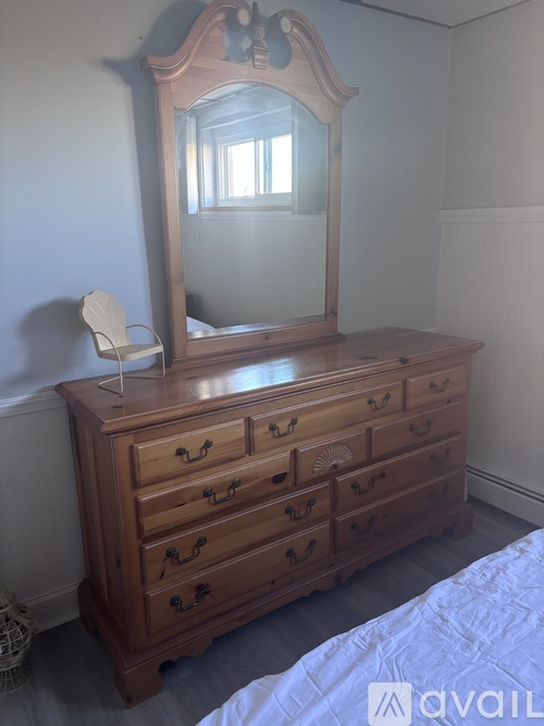 A wooden dresser with a mirror above it and a chair beside it.