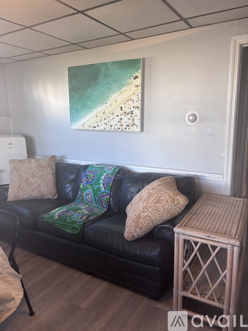 A living room with a black couch and a painting on the wall.