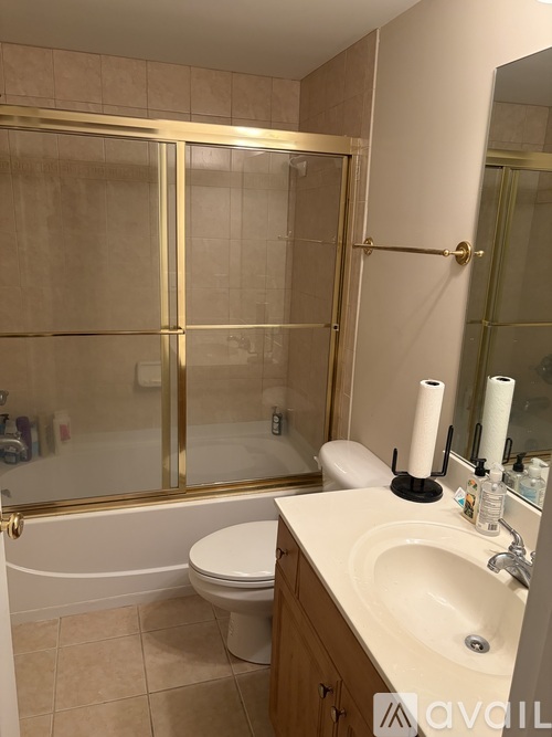 A bathroom with a toilet, sink, and a glass shower stall.
