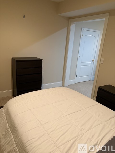 A bedroom with a bed, dresser and door.