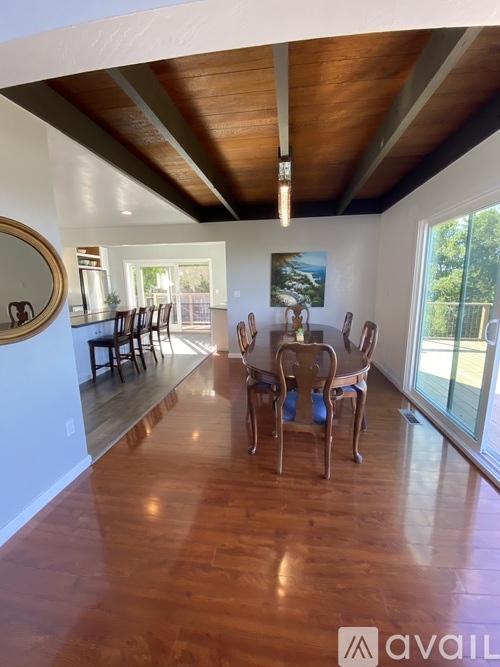 A dining room with a wooden floor and a large mirror on the wall.
