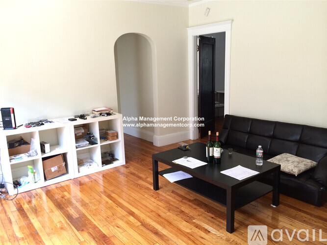 A living room with a black couch and a coffee table with a bottle of wine on it.