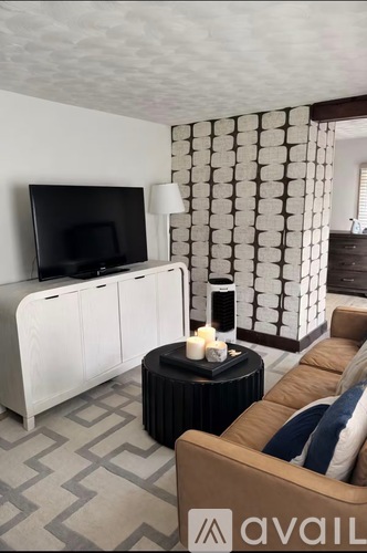 A living room with a television, a sofa, and a table with candles on it.