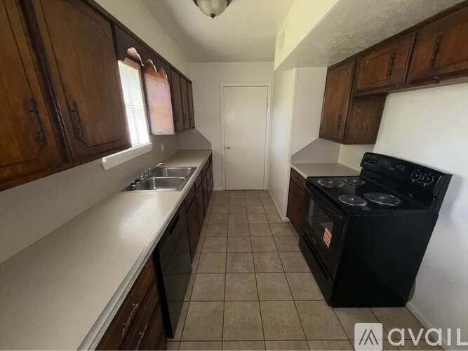 A kitchen with a black stove top oven and brown cabinets.
