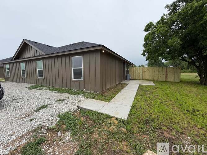 A house with a brown siding and a gravel driveway.