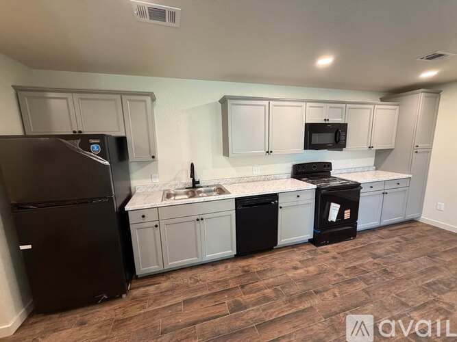 A kitchen with a black fridge, black dishwasher, and black oven.