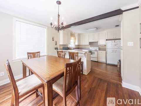 A kitchen with a table and chairs in the foreground and a refrigerator with a magnet on it in the background.