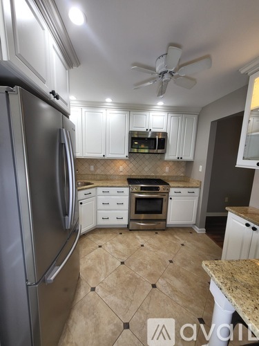 A kitchen with a tile floor and a ceiling fan.