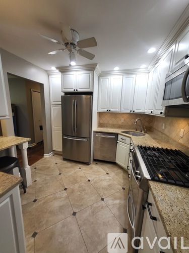 A kitchen with a tile floor and a stainless steel refrigerator.
