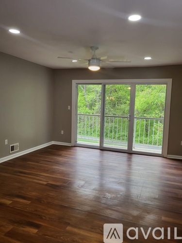A room with wooden floors and a sliding glass door leading to a balcony.
