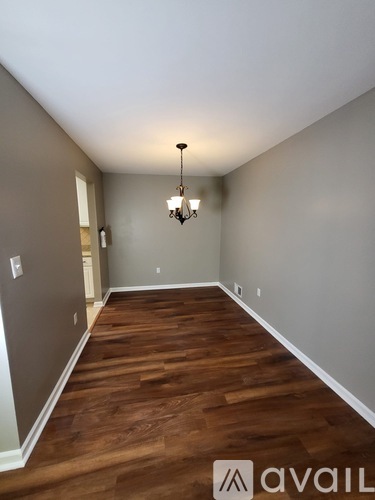 A long hallway with wood floors and a chandelier.