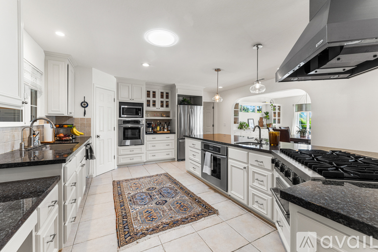 A kitchen with white cabinets and black countertops.