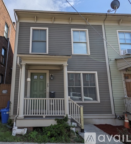 A grey house with a green door and a white railing.