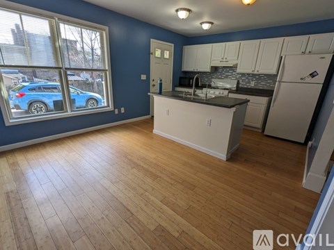A kitchen with a blue wall and wooden flooring.