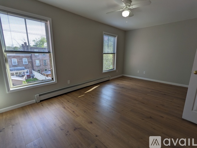 A room with wooden floors and a window showing a view of a building outside.