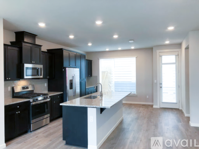 A modern kitchen with dark cabinets and stainless steel appliances.