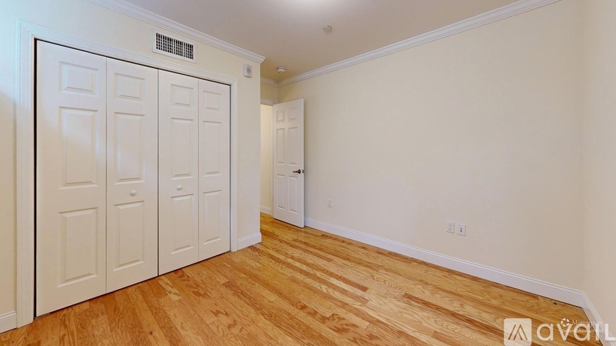 A room with a white door and wooden flooring.