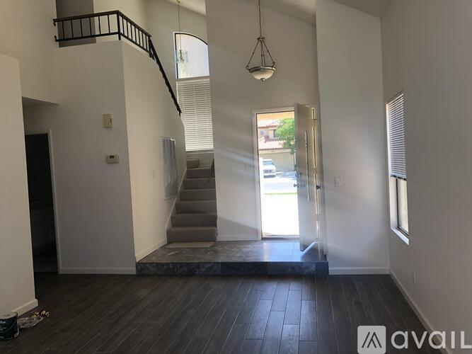 A living room with a staircase and a hanging light fixture.