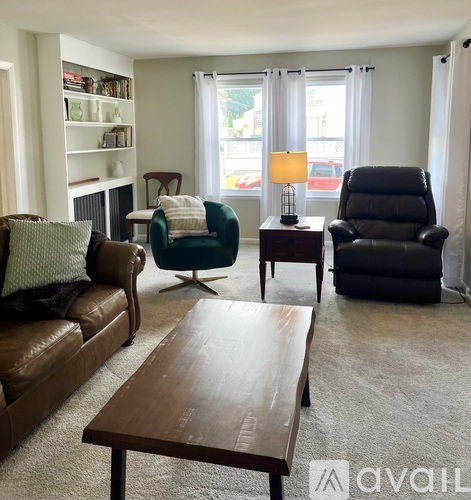 A living room with a brown leather couch and a green bookshelf.