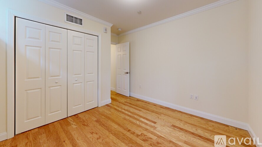 A room with a white door and wooden flooring.