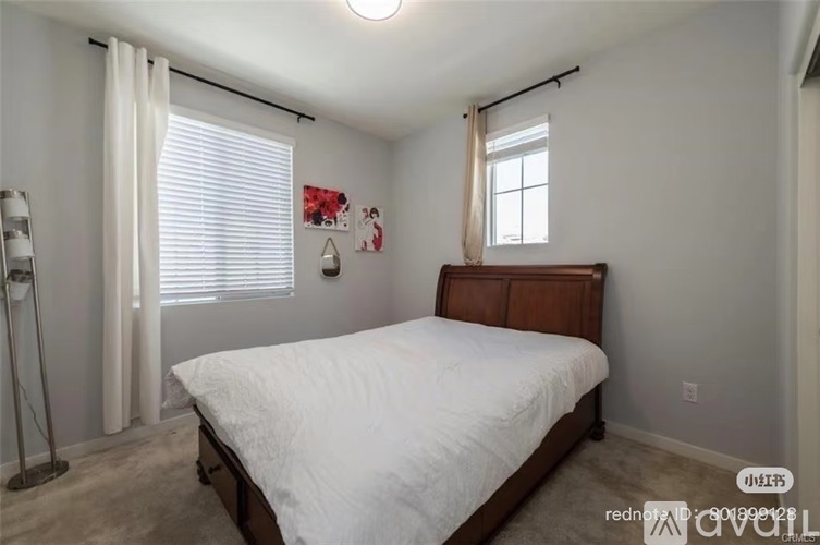 A bedroom with a bed, a window with blinds, and a lamp.