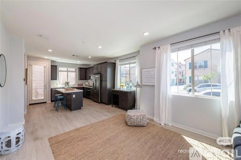 A well-lit, spacious kitchen and living room with a dining table and chairs.