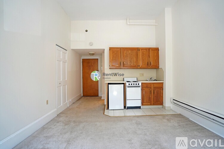 A kitchen with white appliances and wooden cabinets is available for rent.