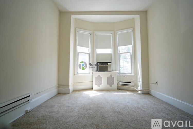 A room with a carpeted floor and a window with blinds.