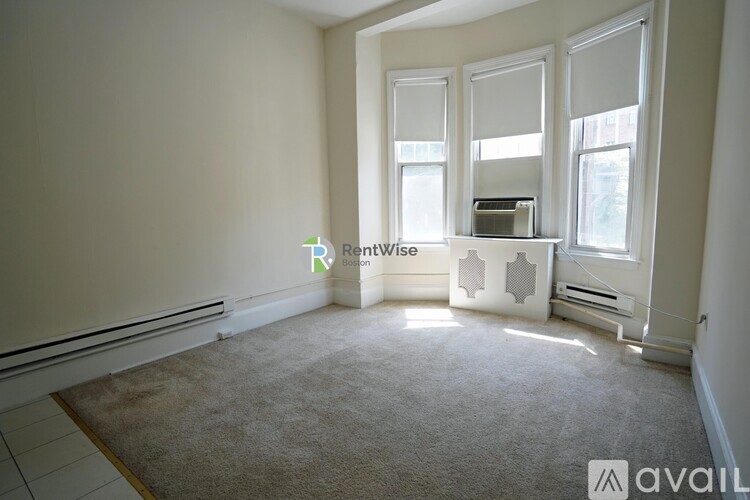 A room with a carpeted floor and a window with blinds.